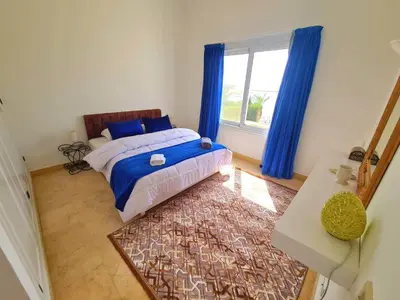 a bedroom with a bed and a window with blue curtains at White villa in Hurghada