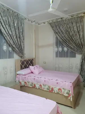 two beds in a room with pink sheets and curtains at Queen Feryal in Jazīrat Aswān