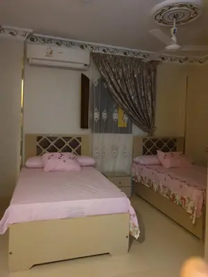 a bedroom with two beds with pink sheets at Queen Feryal in Jazīrat Aswān