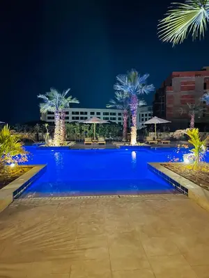 a swimming pool with palm trees in front of a building at Hurghada Stylish Heaven Luxury Apartment in Hurghada