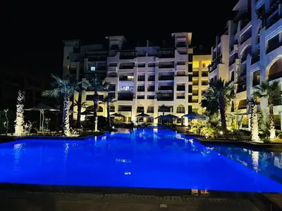 a large blue pool in front of a building at night at Hurghada Stylish Heaven Luxury Apartment in Hurghada