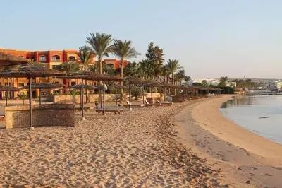 a beach with umbrellas and chairs and the ocean at Esplanadа Apartments in Hurghada