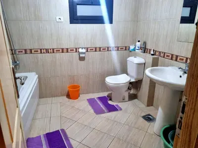a bathroom with a toilet and a sink with purple mats at Esplanadа Apartments in Hurghada