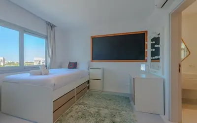 a small bedroom with a bed and a large window at Relax in Style I Lagoon-Front 2BR in Swan Lake El Gouna in Hurghada
