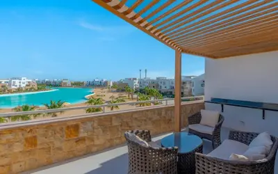a balcony with chairs and a view of the water at Relax in Style I Lagoon-Front 2BR in Swan Lake El Gouna in Hurghada