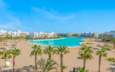 a view of a beach with palm trees and buildings at Relax in Style I Lagoon-Front 2BR in Swan Lake El Gouna in Hurghada