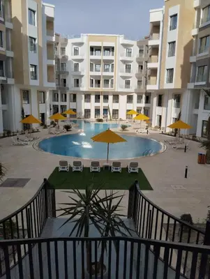 a swimming pool with chairs and umbrellas in front of a building at Studiowohnung Aqua Infinity in Hurghada