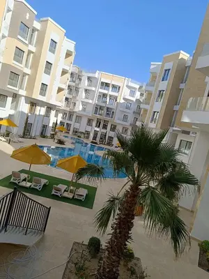 a palm tree in front of a large apartment building at Studiowohnung Aqua Infinity in Hurghada