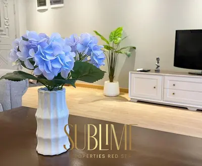 a vase with blue flowers in a living room at Tawaya 1br with sea view in Hurghada
