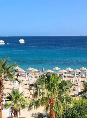 a beach with chairs and umbrellas and the ocean at Tawaya 1br with sea view in Hurghada