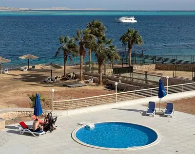 a group of people sitting in chairs next to a swimming pool at Studio By The Beach in Hurghada