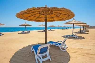 a beach with chairs and an umbrella and the ocean at Studio By The Beach in Hurghada
