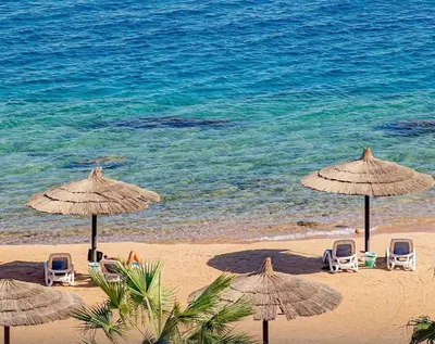 a group of chairs and umbrellas on a beach at Studio By The Beach in Hurghada