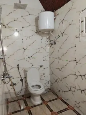 a bathroom with a toilet and a white marble wall at Makky ka in Jazīrat Suhayl