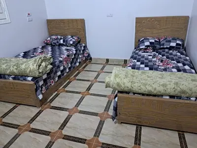 two beds in a room with a tiled floor at Makky ka in Jazīrat Suhayl