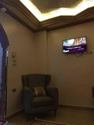 a living room with a chair and a tv on the wall at شقة فاخرة خلف الاستاد اسوان in Aswan