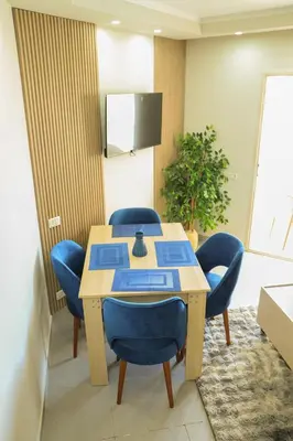 a room with a table with blue chairs and a tv at Angeli Apartment Scandic Rezort in Hurghada