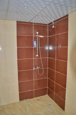 a bathroom with a shower with brown tile at Kinga Apartment Florenza Khamsin in Hurghada