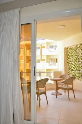 a sliding glass door with chairs and a table at Kinga Apartment Florenza Khamsin in Hurghada