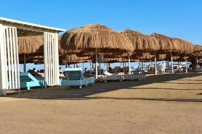a group of straw umbrellas and chairs on the beach at Hurghada Princess resort, Private Sandy Beach & 3 Pools in Hurghada