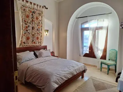 a bedroom with a bed and a window and a chair at Bella Sabina, Lovely one bedroom chalet with pool in Hurghada