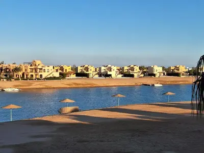 a group of umbrellas on a beach with buildings at Bella Sabina, Lovely one bedroom chalet with pool in Hurghada
