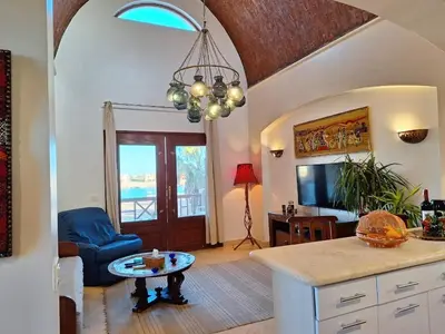 a kitchen with a table and a living room at Bella Sabina, Lovely one bedroom chalet with pool in Hurghada