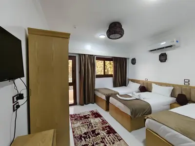 a hotel room with two beds and a television at JJ Guesthouse in Aswan