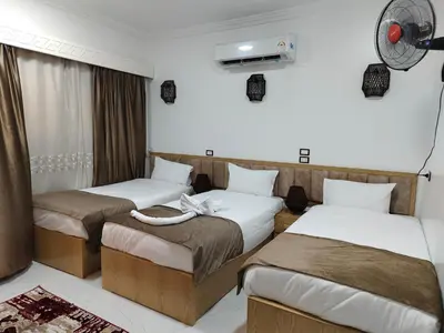 a hotel room with two beds and a fan at JJ Guesthouse in Aswan