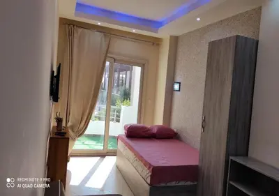 a bedroom with a bed and a window with a balcony at Lovely APT Sunny Beach Front, Near Senzo Mall Free WIFI in Hurghada