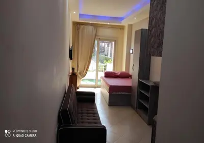 a bedroom with a bed and a couch and a window at Lovely APT Sunny Beach Front, Near Senzo Mall Free WIFI in Hurghada