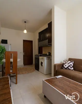 a living room with a couch a table and a kitchen at Cosy flat in Makadi heights in Hurghada