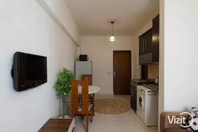 a kitchen with a table and a tv on a wall at Cosy flat in Makadi heights in Hurghada