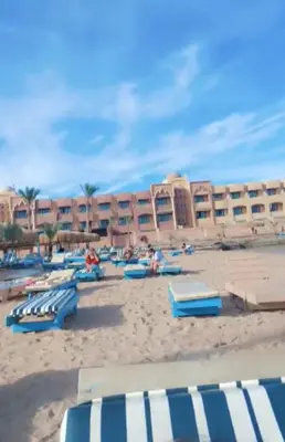a beach with blue and white chairs and a building at شالية بقرية الذهبية in Hurghada