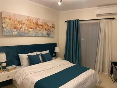a bedroom with a bed with a blue head board at Modern Apartment with Direct Pool Access in Aqua Tropical in Hurghada