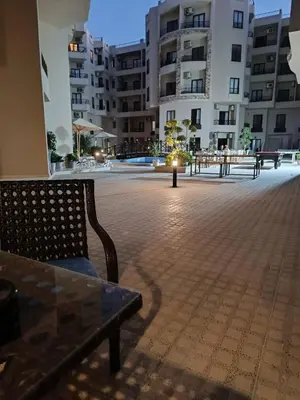 a group of benches in a courtyard with buildings at Modern Apartment with Direct Pool Access in Aqua Tropical in Hurghada