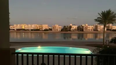 a swimming pool in front of a large body of water at SunShine Joubal view in Hurghada