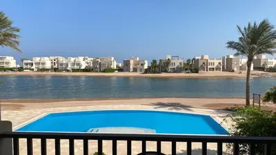 a swimming pool next to a body of water with buildings at SunShine Joubal view in Hurghada