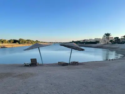 two chairs and umbrellas on a beach with water at SunShine Y1-0-6 in Hurghada