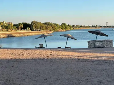 three benches and umbrellas on a beach near a body of water at SunShine Y1-0-6 in Hurghada