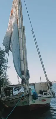 a boat with a sail in the water at Nile Bride Felucca in Aswan