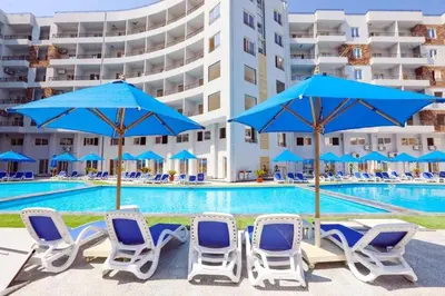 a group of chairs and umbrellas next to a swimming pool at Tiba Golden Resort in Hurghada