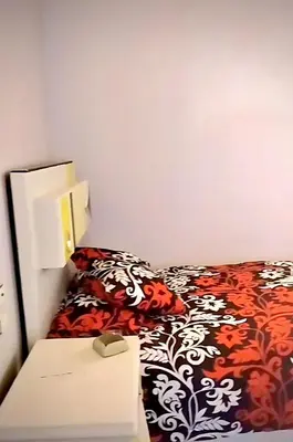 a bed with a red and white blanket and a night stand at Nuba in Aswan