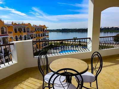 a table and chairs on a balcony with a view of the water at Stunning Nile view Apartment in Luxor
