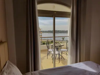 a bedroom with a bed and a balcony with a table and chairs at Stunning Nile view Apartment in Luxor