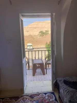 a room with a door open to a balcony with a table at Habu House Luxor in Luxor