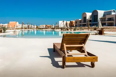 a wooden chair sitting in front of a swimming pool at Prim & Pleasing 1BDR Kamaran El Gouna in Hurghada