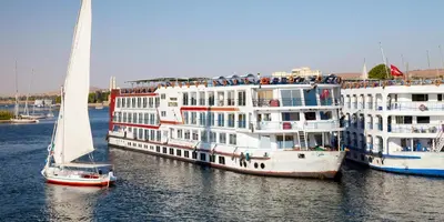 two cruise ships in the water with a sail boat at 4 Days Nile Cruise from Luxor to Aswan in Luxor