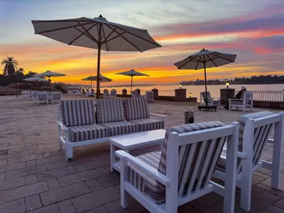 a group of chairs and umbrellas on the beach at sunset at Nile view Apartment in Luxor