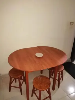 a wooden table with two stools and a table and chairs at Al Dahar apartments Hurghada in Hurghada